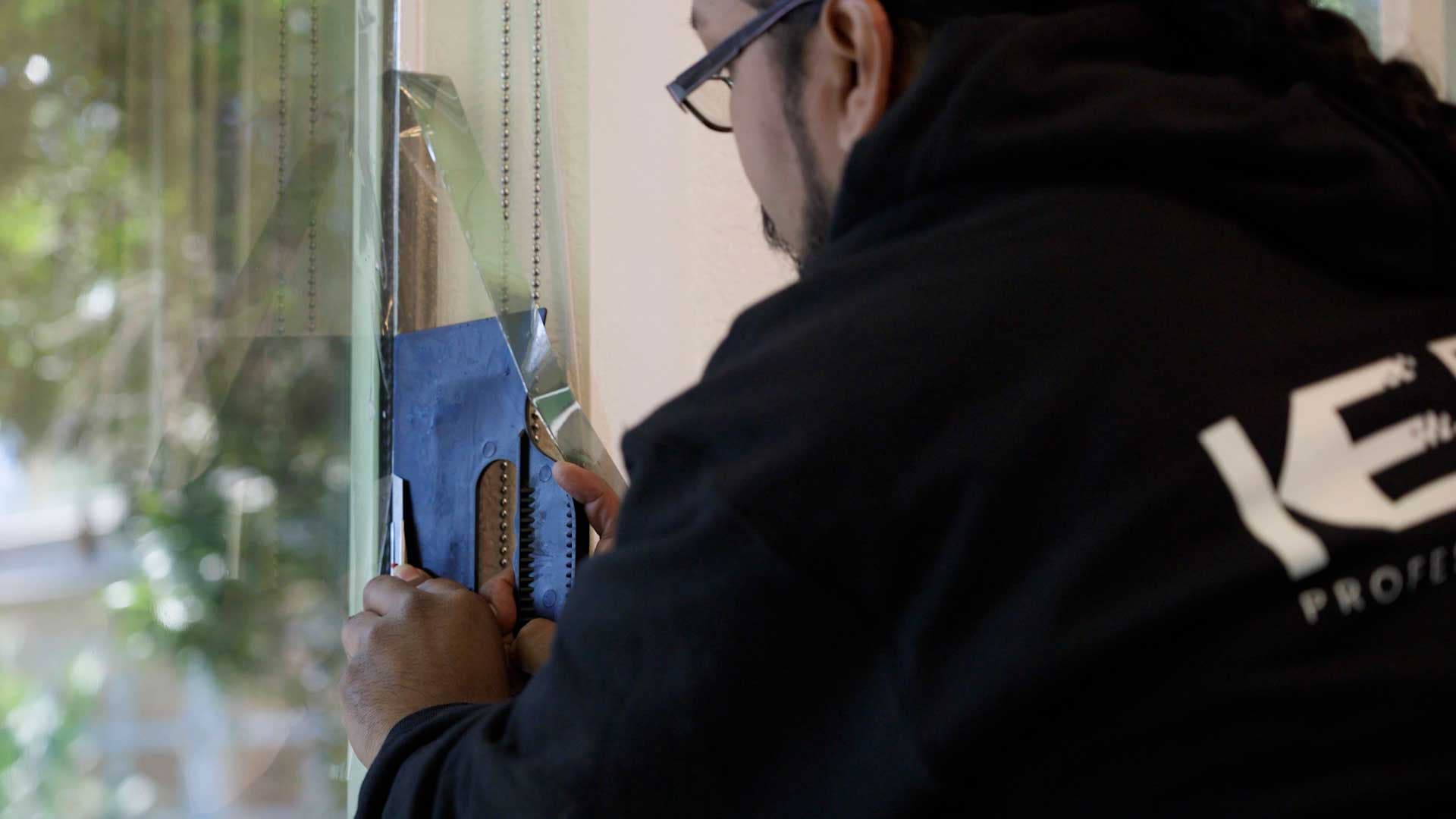 Installer applying film to large windows